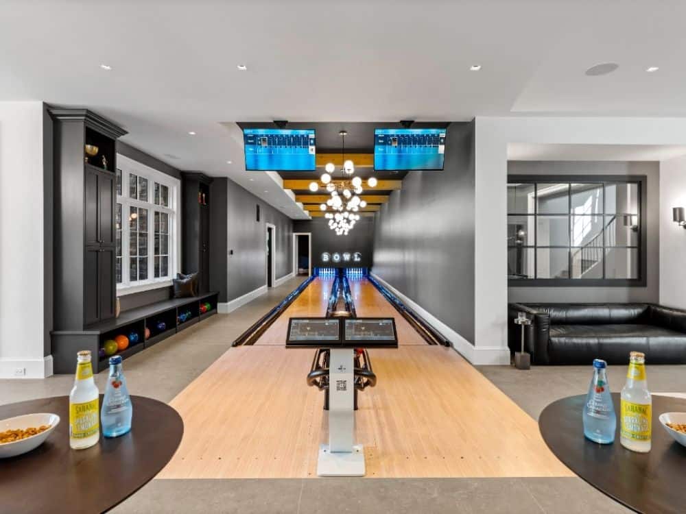Custom home bowling alley equipment featuring two ten pin bowling lanes with modern scoring systems in a luxury residential entertainment space.