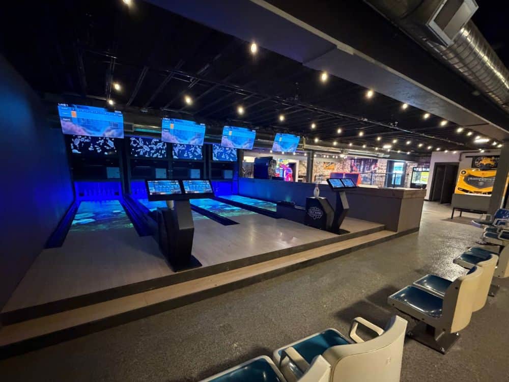 Six duckpin arcade bowling lanes with blue lighting, on-lane projection, and digital scoring screens at Midtown Market in Cambridge, Ohio.